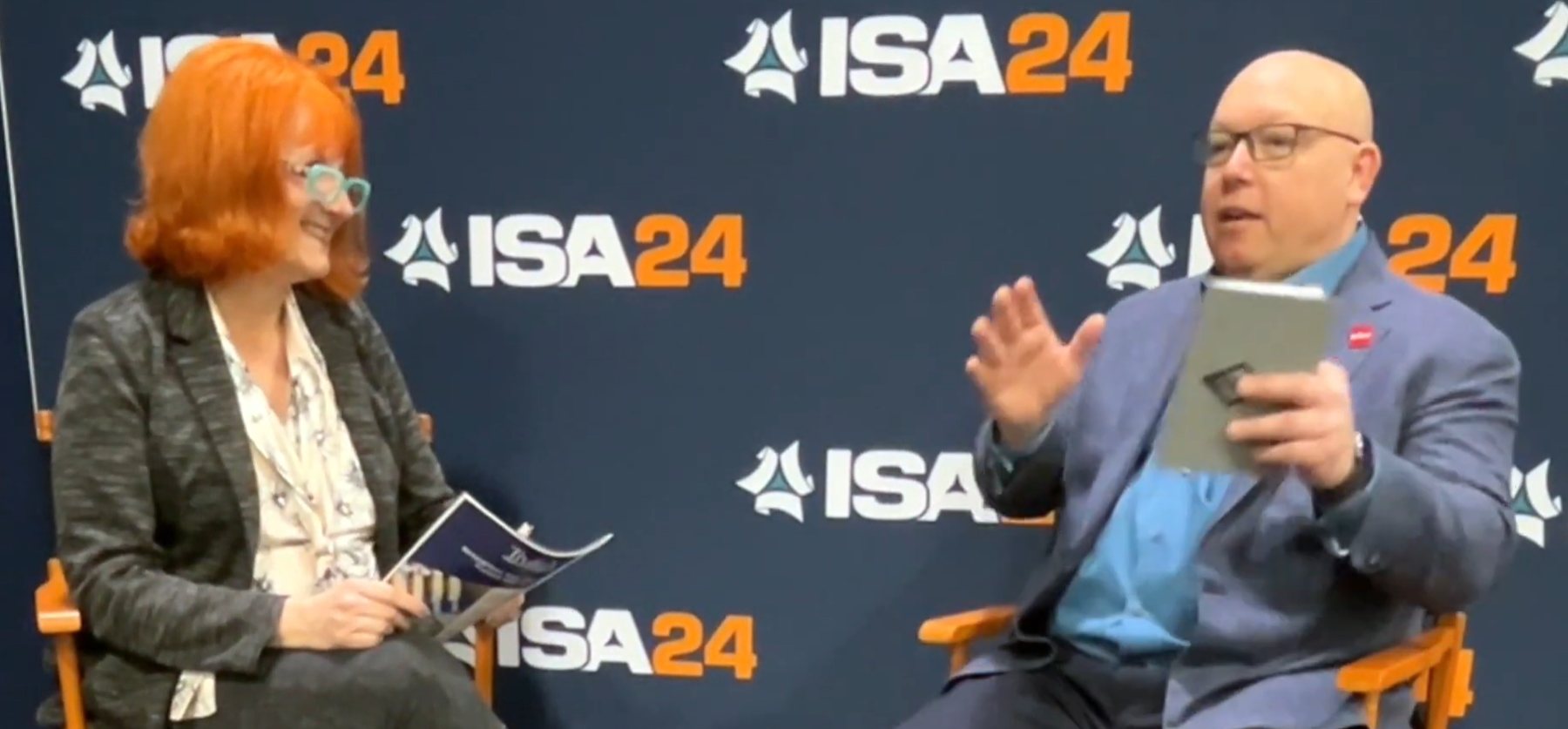 Will Quinn being interviewed on stage at ISA24 in front of an ISA24 backdrop